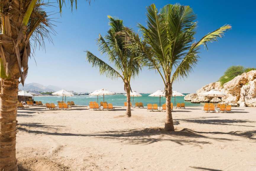 Ein Strand mit vielen Stühlen und Sonnenschirmen