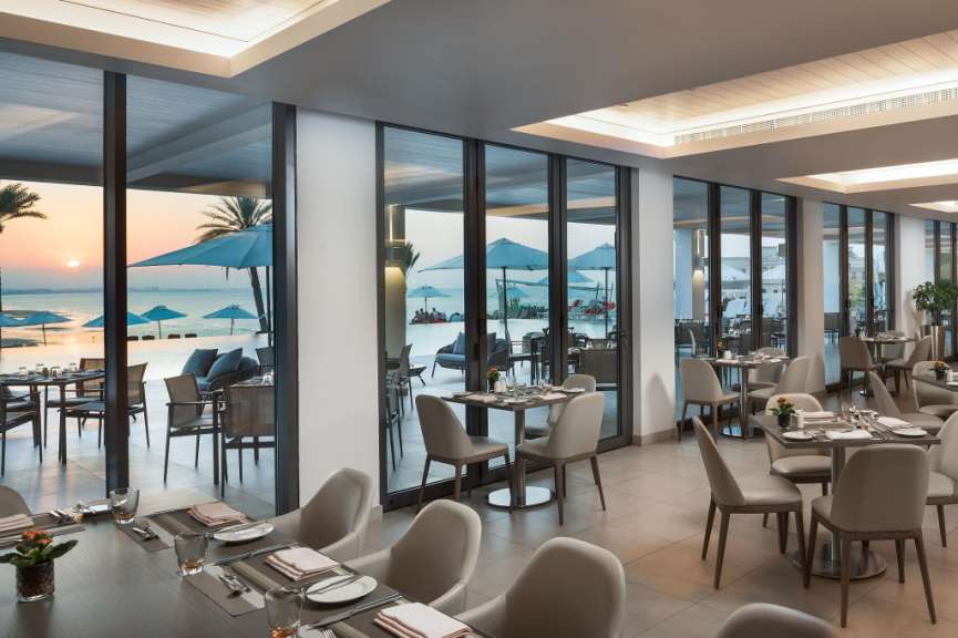 Ein Restaurant mit vielen Tischen und Stühlen mit Blick auf das Meer