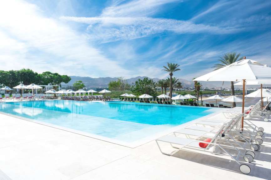 Ein großer Pool mit vielen weißen Sonnenschirmen umgeben