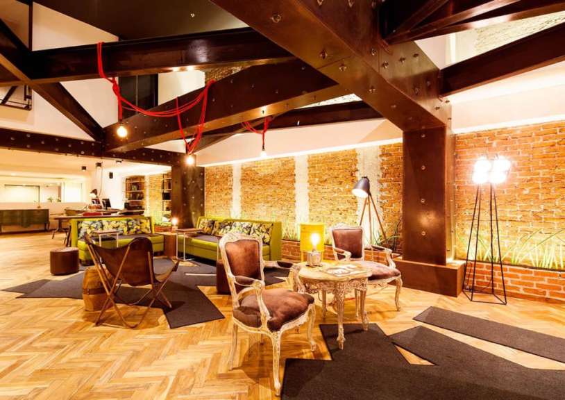 Ein moderner Loungebereich mit sichtbaren Stahlträgern, Ziegelwänden und Retro-Möbeln.