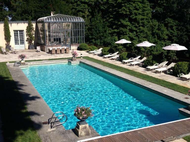 Ein großer Swimmingpool mit Liegestühlen und Sonnenschirmen umgeben