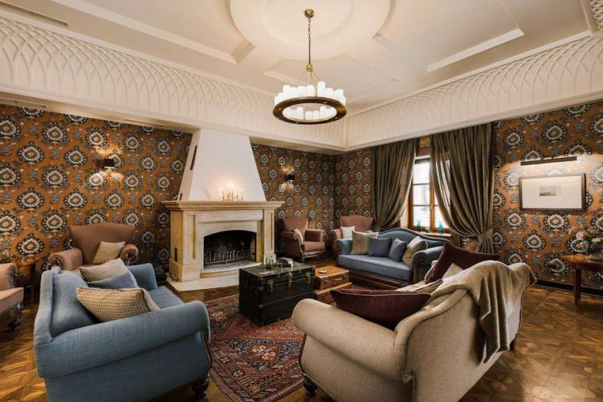 Ein luxuriöser Salon mit Kaminsims, Sitzgelegenheiten und auffälliger Tapete.
