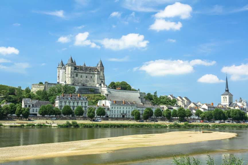 Ein großes Schloss sitzt auf einem Hügel über einem Fluss