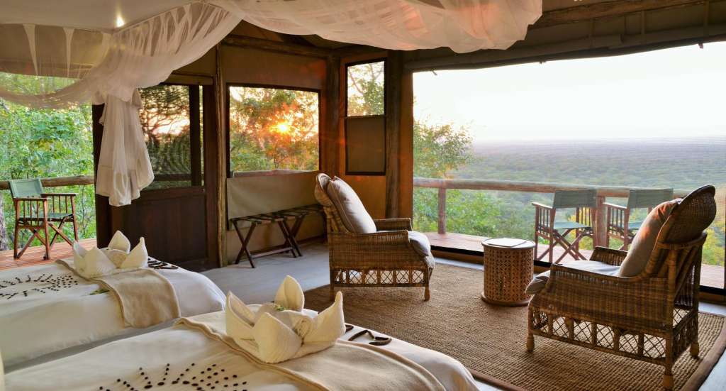 Ein Zimmer mit zwei Betten und zwei Stühlen mit Blick auf den Dschungel