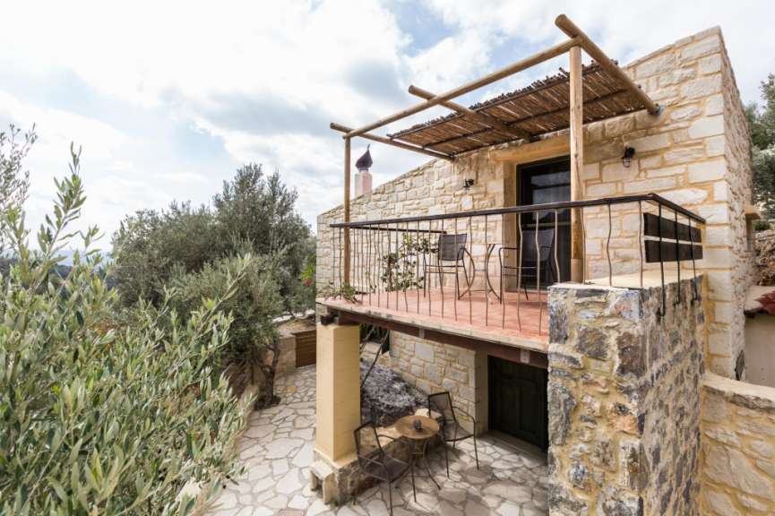 Ein Steinhaus mit einem Balkon mit Stühlen und einem Tisch