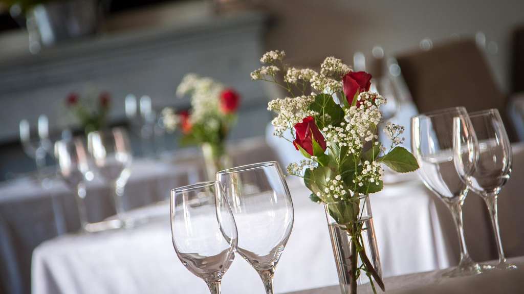 Ein Tisch mit weingläsern und einer vase mit roten rosen