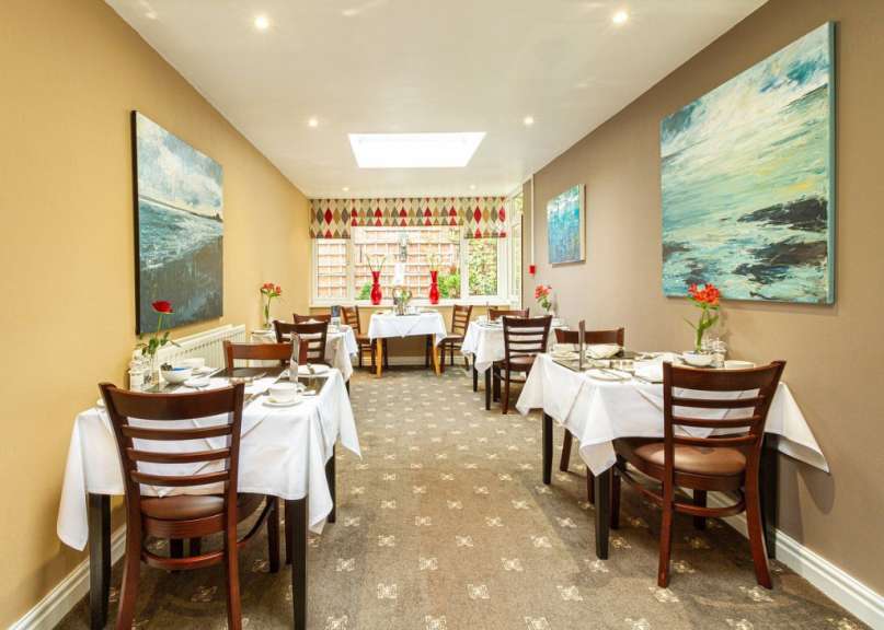 Ein Esszimmer mit Tischen und Stühlen und Gemälden an den Wänden