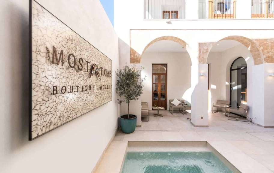 Ein weißes Gebäude mit einem Pool und einem Schild, das sagt boutique hotel