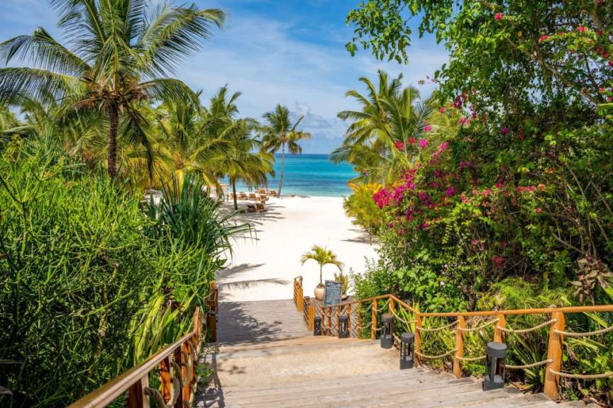 Eine Holztreppe führt zu einem weißen Sandstrand