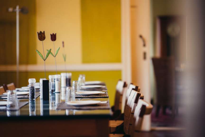 Ein langer tisch mit tellern und gläsern steht in einem raum mit gelben wänden