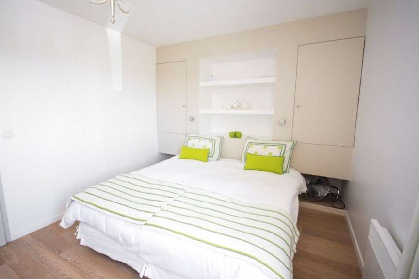 Ein Schlafzimmer mit weißem Bett und grünen Kissen