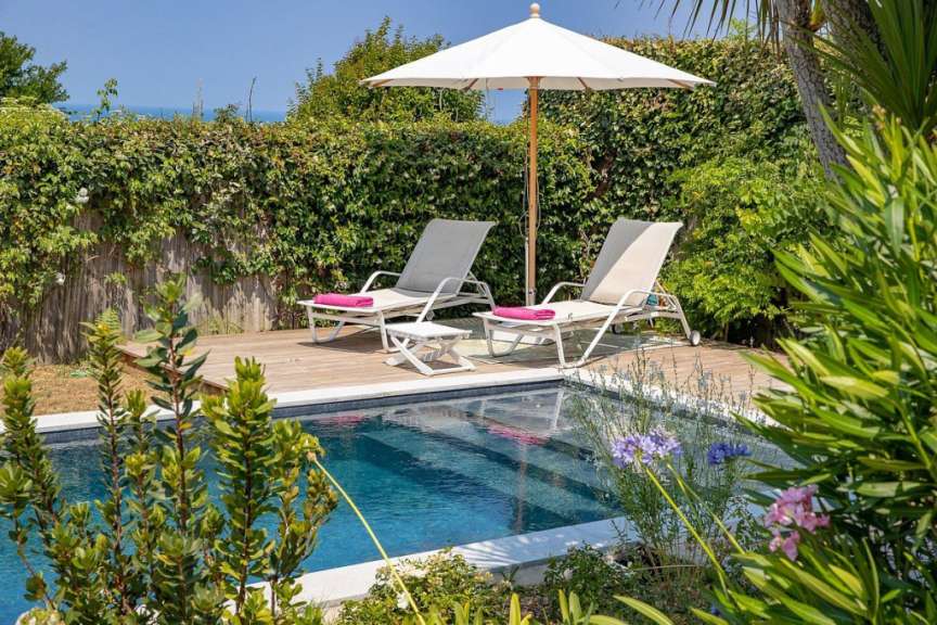 Ein Swimmingpool mit Liegestühlen und einem weißen Regenschirm
