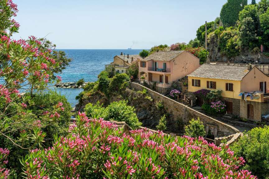 Ein rosa und gelbes Haus auf einem Hügel mit Blick auf das Meer