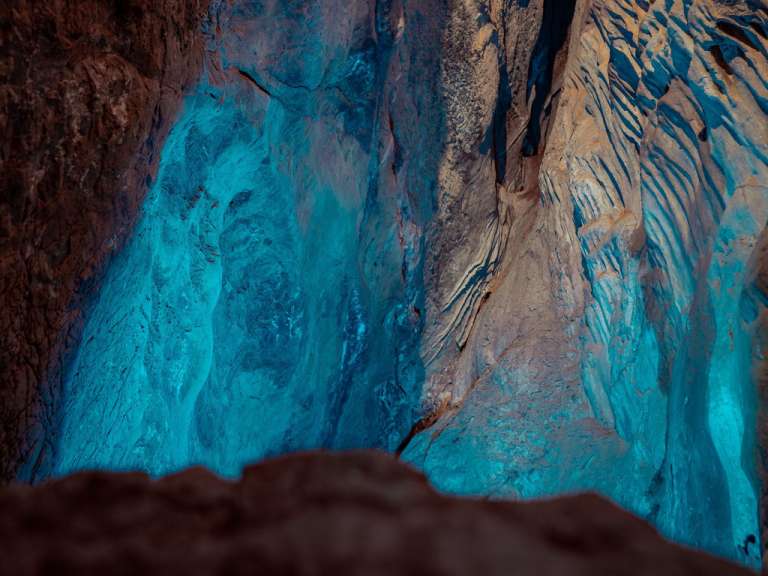 Ein Höhleninneres wird von blauem Licht beleuchtet, das die Felsformationen hervorhebt.