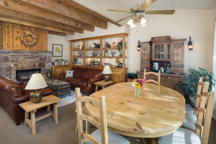 In diesem Bild wird ein rustikales Wohnzimmer mit einem Steinkamin, Ledermöbeln und einem Holztisch gezeigt.