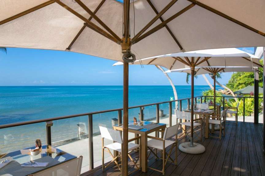 Tische und Stühle auf einem Deck mit Blick auf das Meer