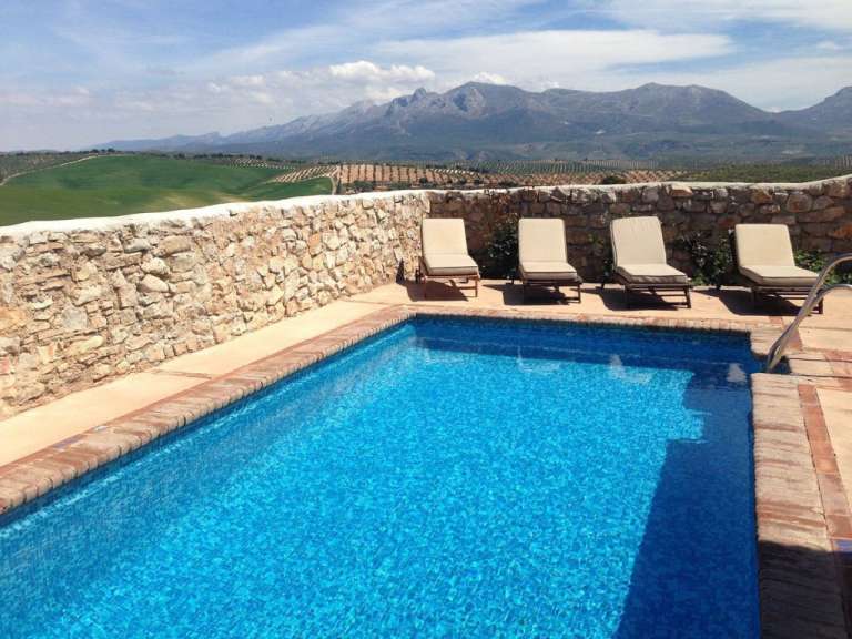 Ein Swimmingpool mit Liegestühlen und einer Steinmauer im Hintergrund