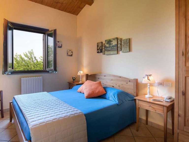 Ein Schlafzimmer mit einem blauen Bett und einem Fenster