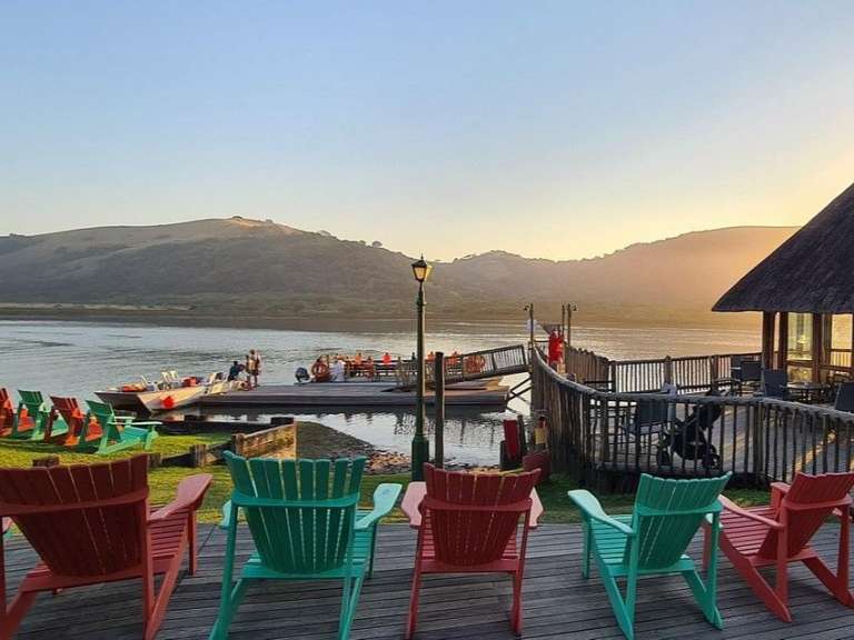 Eine Reihe von bunten Stühlen auf einem Deck mit Blick auf einen See