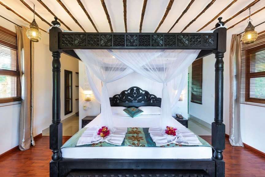 Ein Schlafzimmer mit einem Himmelbett und vielen Fenstern