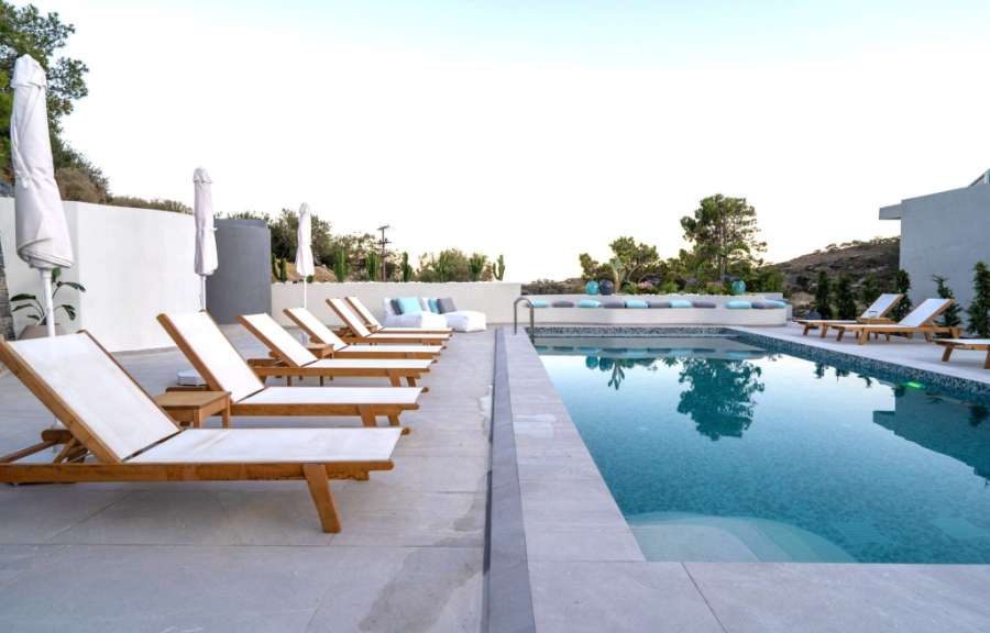 Ein Swimmingpool mit Liegestühlen und Sonnenschirmen umgeben