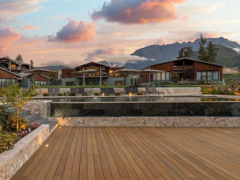 Ein großer Swimmingpool steht vor einem Hotel mit Bergen im Hintergrund