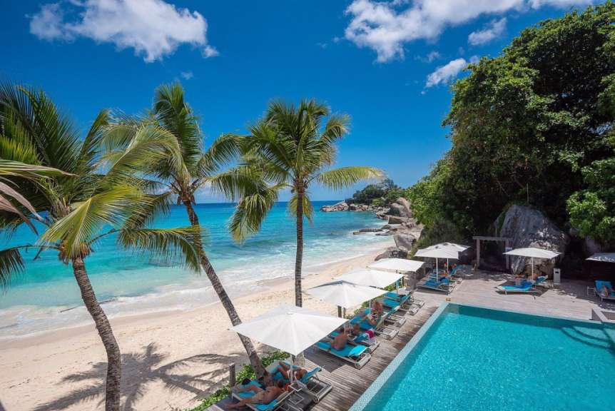 Eine Gruppe von Menschen sitzt neben einem Swimmingpool am Strand