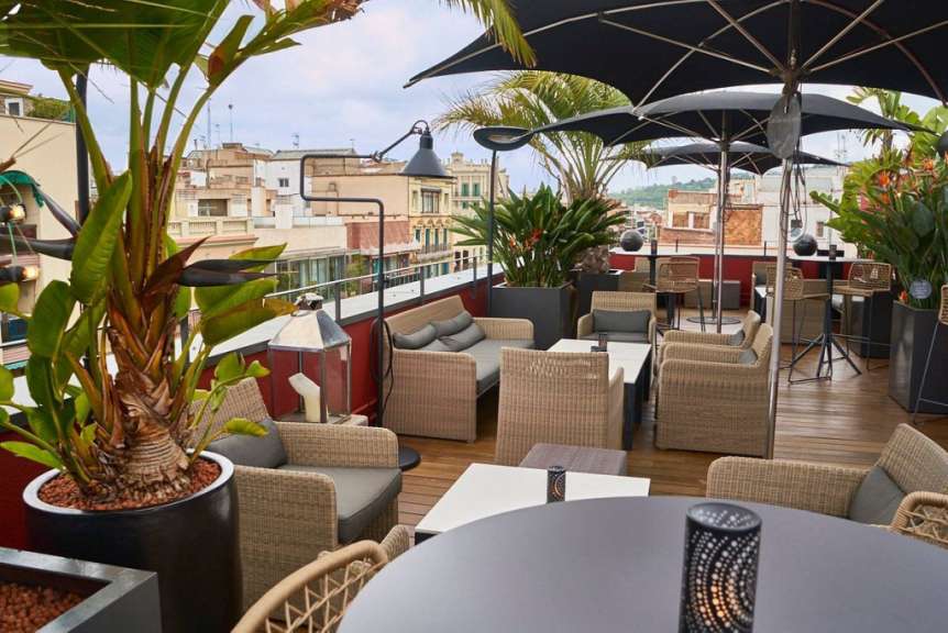 Eine Terrasse mit Tischen und Stühlen und schwarzen Regenschirmen