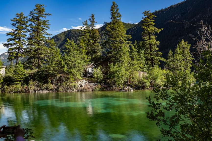 Eine Person nimmt ein Bild von einem See mit Bäumen im Hintergrund