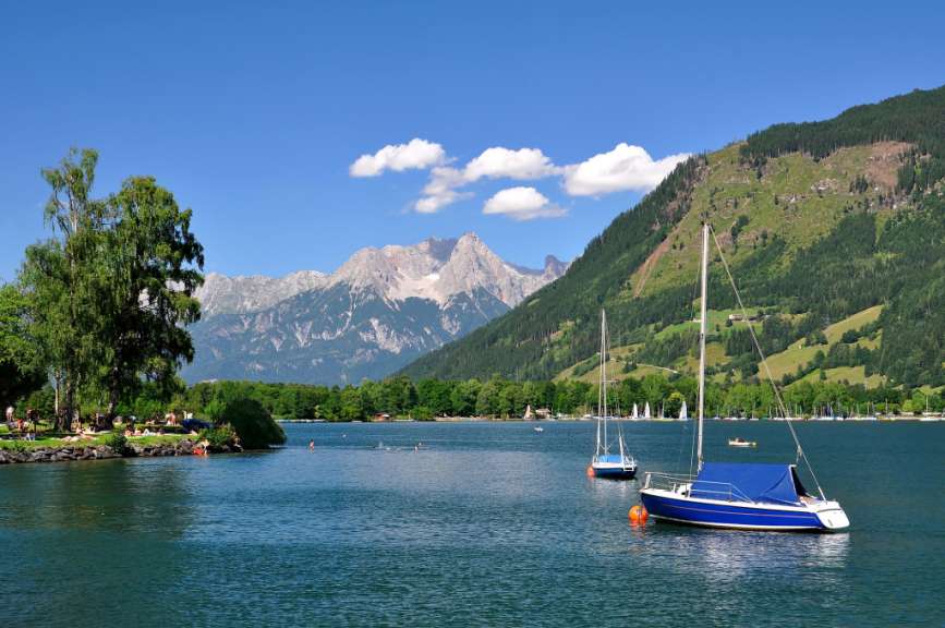 Ein blaues Boot schwimmt in einem See mit Bergen im Hintergrund