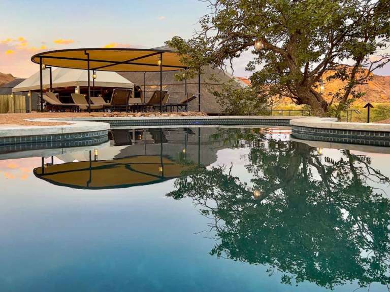Ein Swimmingpool mit einem Zelt und Stühlen im Hintergrund