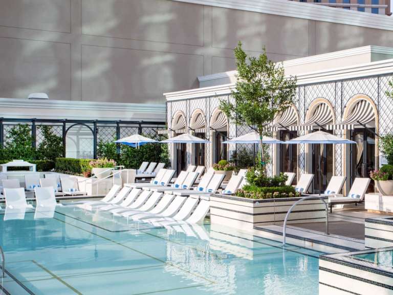 Ein großer Pool mit vielen weißen Stühlen und Regenschirmen