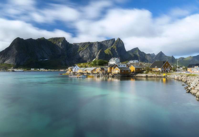 Ein kleines Dorf in der Nähe eines Gewässers mit Bergen im Hintergrund