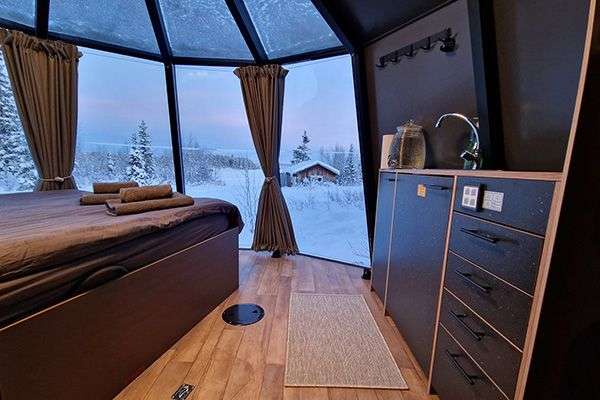 Ein Zimmer mit einem Bett und einem Fenster mit Blick auf den Schnee