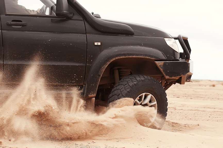 Ein schwarzes Auto fährt durch den Sand