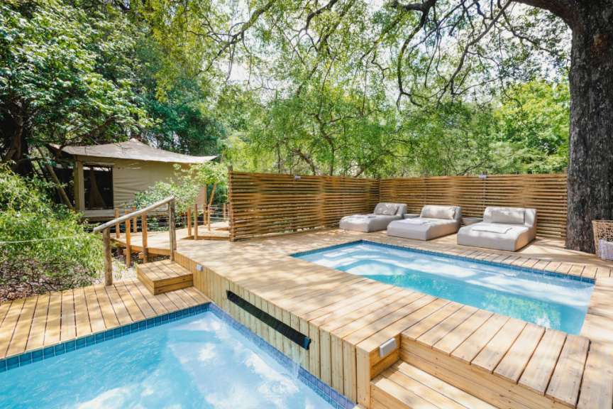 Ein Holzdeck mit einem Pool und Liegestühlen darauf