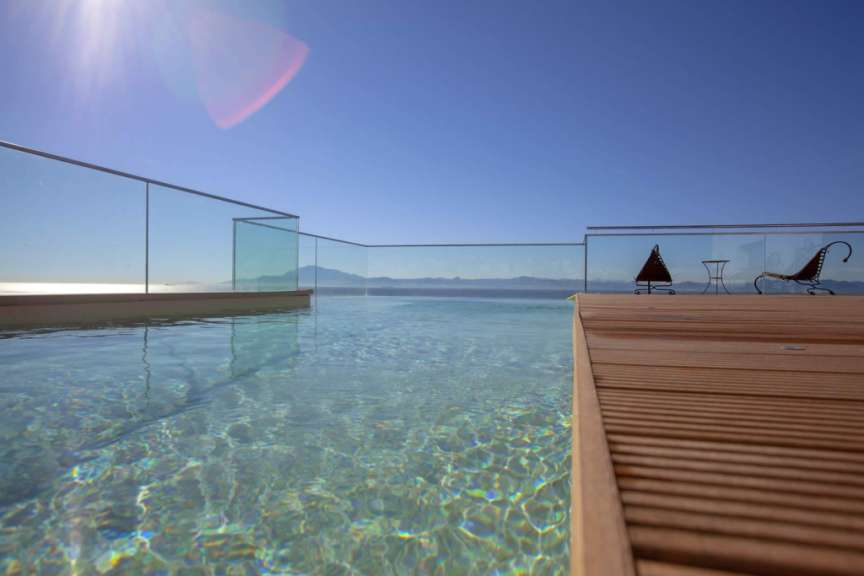 Ein schwimmbad mit einem glasgeländer und einem holzdeck