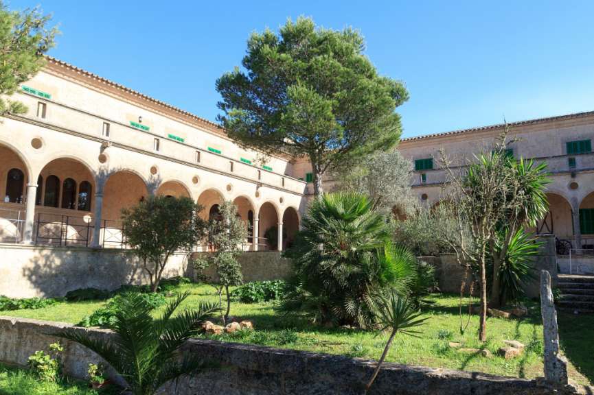 Ein Gebäude mit vielen Bäumen und Pflanzen davor