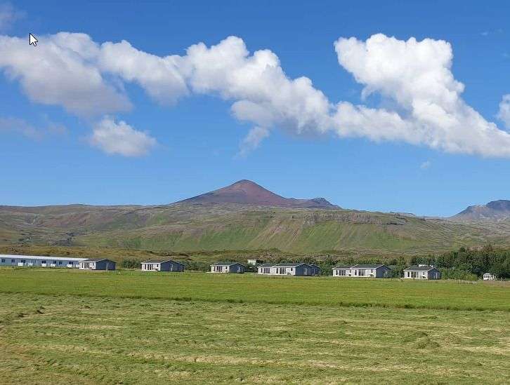 Eine Reihe von Häusern in einem Feld mit einem Berg im Hintergrund