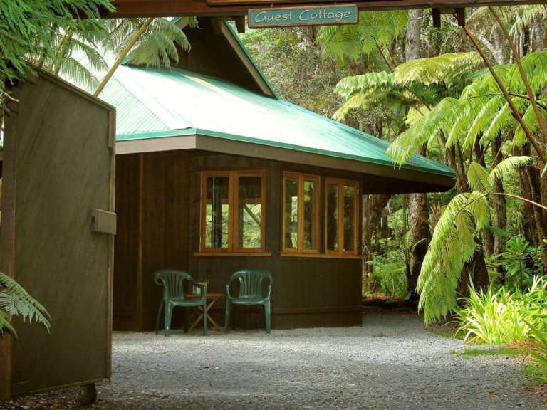 Ein Haus im Wald mit einem Schild darüber , das guest cottage sagt