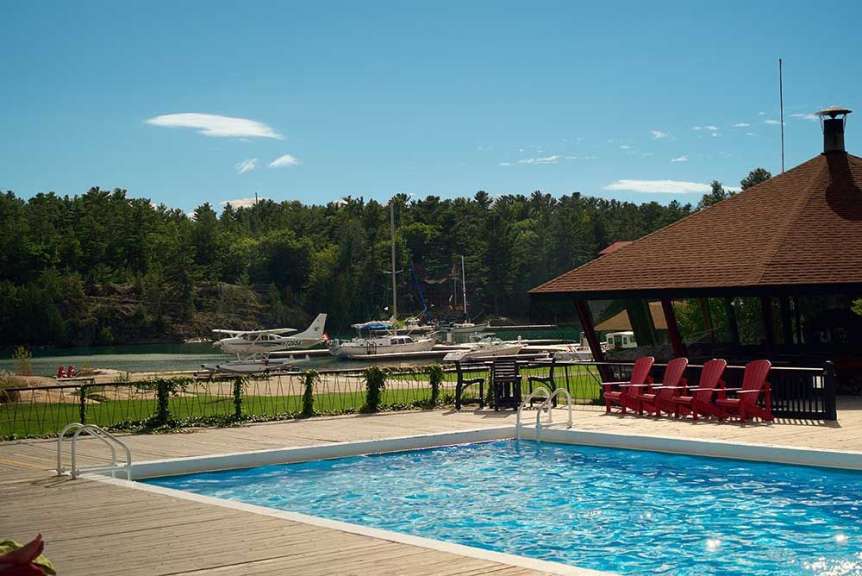 Ein Swimmingpool mit roten Stühlen und Flugzeugen im Hintergrund