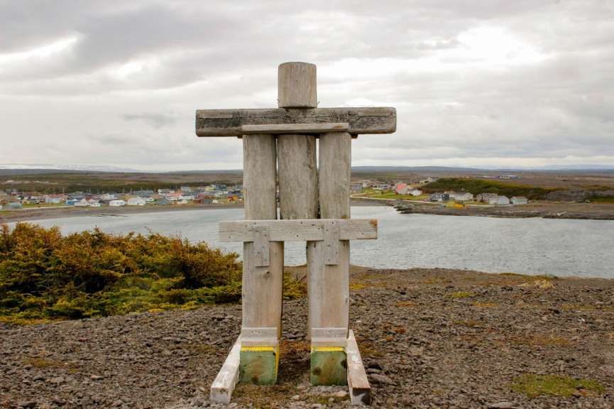 Ein Holzkreuz steht auf einem felsigen Hügel mit Blick auf das Meer