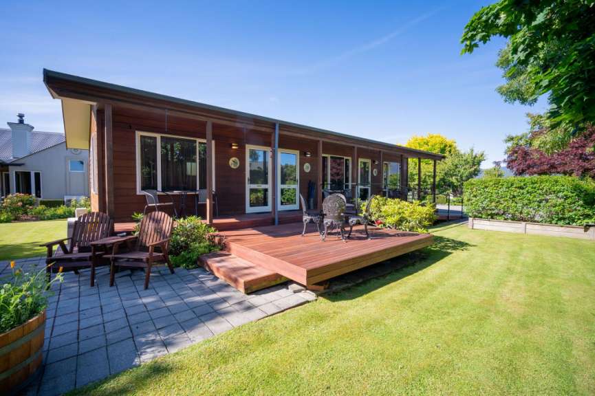 Ein kleines Haus mit einem Holzdeck und Stühlen darauf