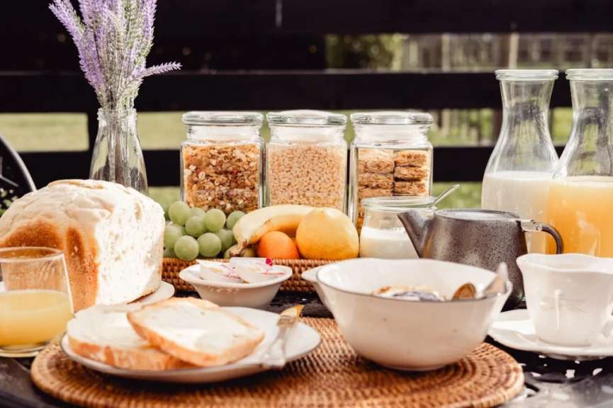 Ein Frühstückstisch mit Brot, Obst, Müsli, Milch und Orangensaft