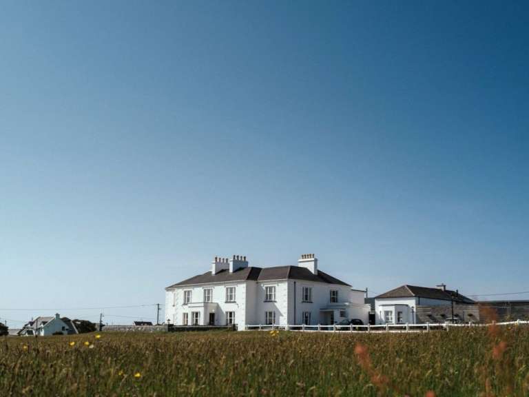 Ein großes weißes Haus steht in einem grasbewachsenen Feld