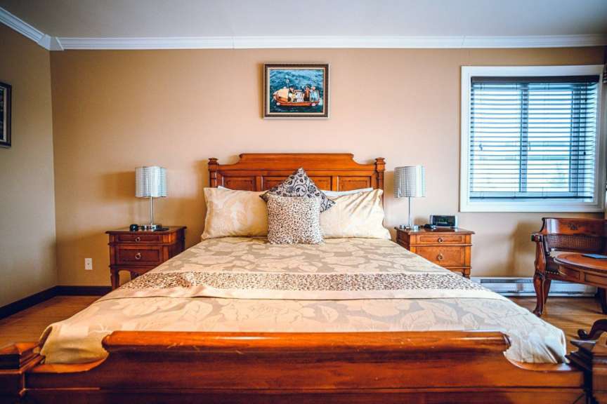Ein Schlafzimmer mit einem Bett und zwei Nachttischen und einem Gemälde an der Wand