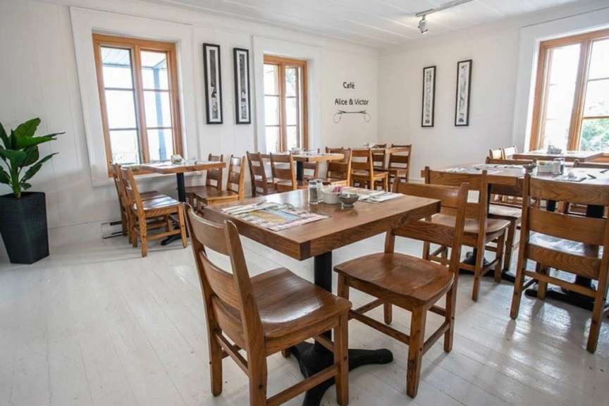 Ein Restaurant mit Holztischen und Stühlen und einem Schild an der Wand mit der Aufschrift „ cafe alice & victor “