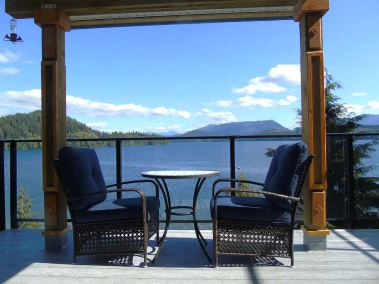 Zwei Stühle und ein Tisch auf einem Deck mit Blick auf einen See