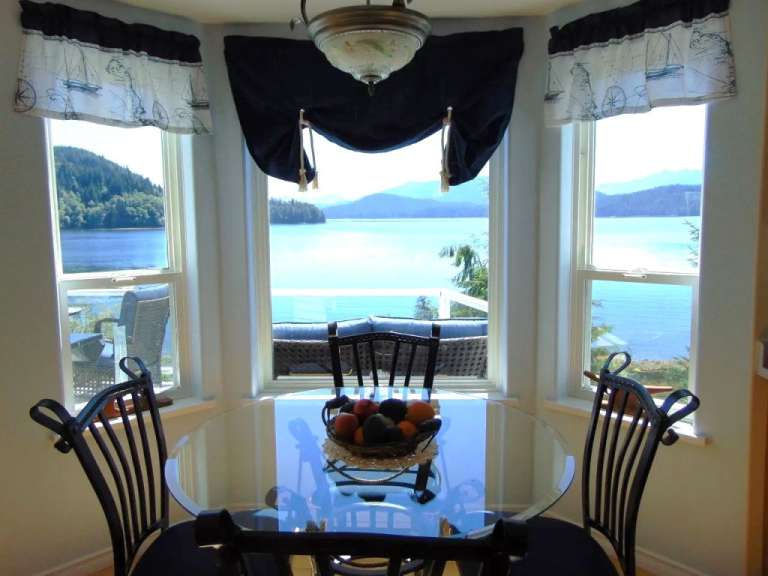 Ein Esszimmer mit einem Tisch und Stühlen mit Blick auf einen See