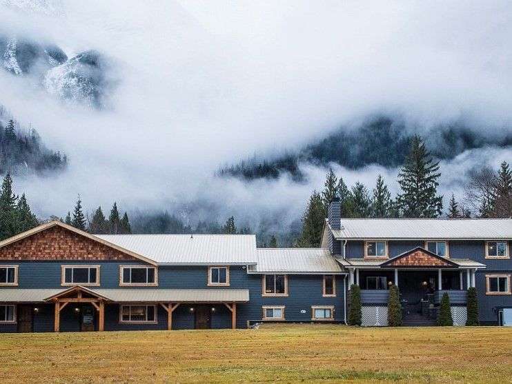 Ein großes Haus steht in einem Feld mit Bergen im Hintergrund